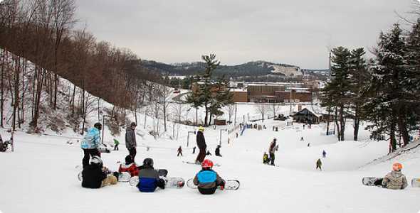 Winter scene at Mulligan's Hollow Ski Bowl in Michigan, showcasing ski slopes bustling with skiers enjoying the winter sports, surrounded by a captivating snowy landscape.
