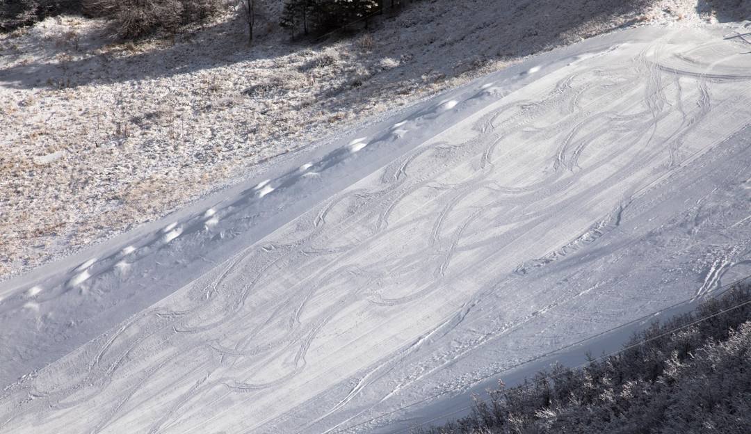 A chalet nestled in Chapman Hill Durango Colorado with a scene of winter sports including a skier and a snowmobile at a bustling ski resort.