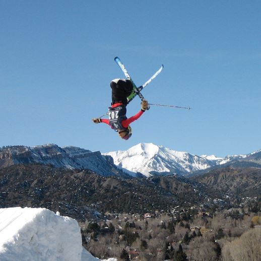 A skier and a snowboarder enjoying the winter sports scene at Chapman Hill, Durango, in Colorado. A ski resort and chalet subtly enhance the snowy background.