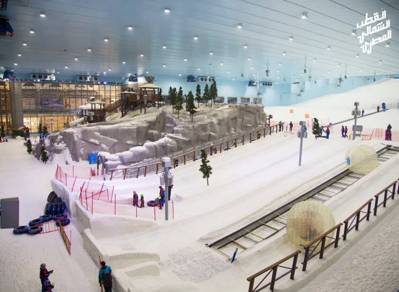 A lively winter sports scene at Ski Egypt with guests enjoying the indoor ski resort. Features include a bustling ski centre, active ski lift and picturesque winter scenery.
