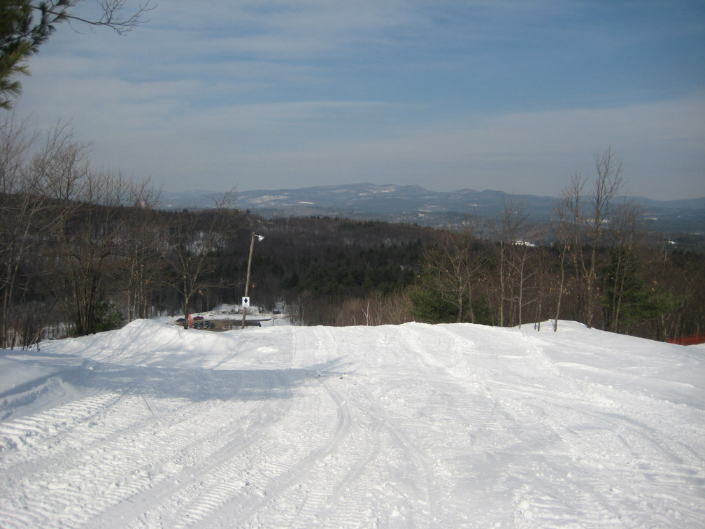A winter sports scene at Veterans Memorial - Franklin New Hampshire showcasing a ski lift ascending towards a cozy chalet with a skier nearby at a ski resort.