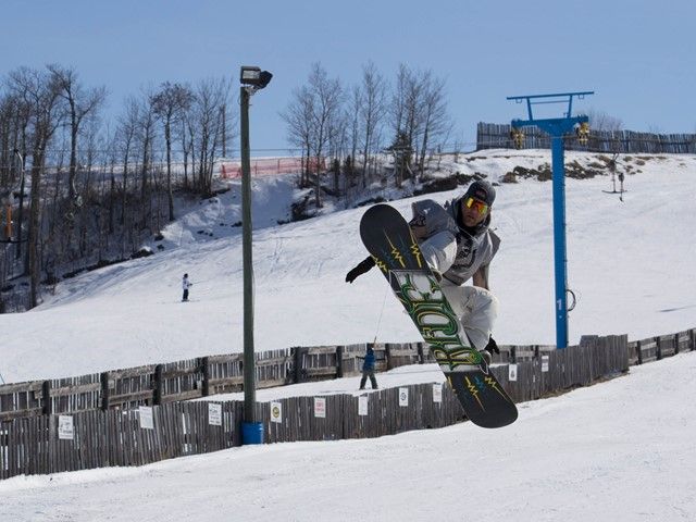 A snowboarder skillfully carving their way down the slopes in Gwynne Valley Central Alberta amidst stunning white snow and clear skies. A perfect winter sporting day in Canada.