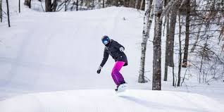 A snowboarder skillfully navigating down Paul Bunyan Ski Hill in Wisconsin, USA, amidst a beautiful white winter landscape.