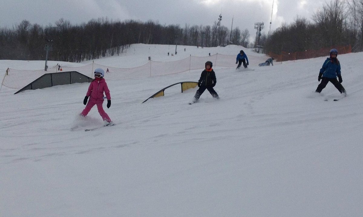 Mt Pisgah in USA - a group of people skiing down a snow covered slope.