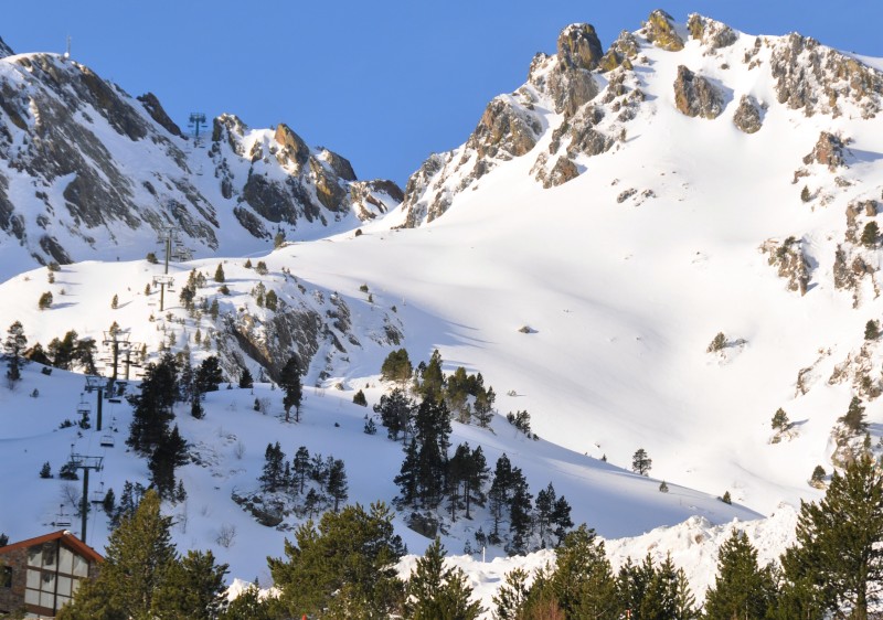 View of Ordino Arcalís featuring a picturesque chalet nestled against a snow-covered mountain, with ski resort facilities and winter sports enthusiasts enjoying the slopes.