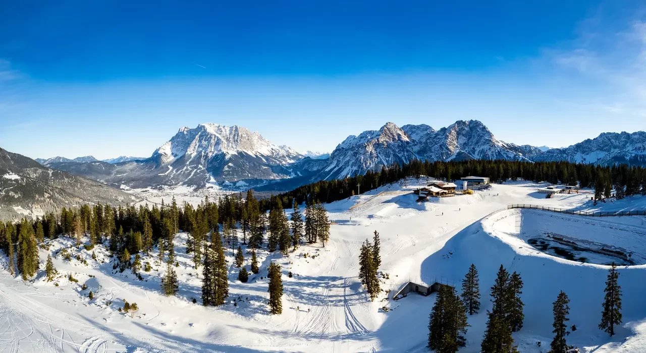 Karlift – Heiterwang in Austria - a snow covered mountain with trees and mountains in the background.