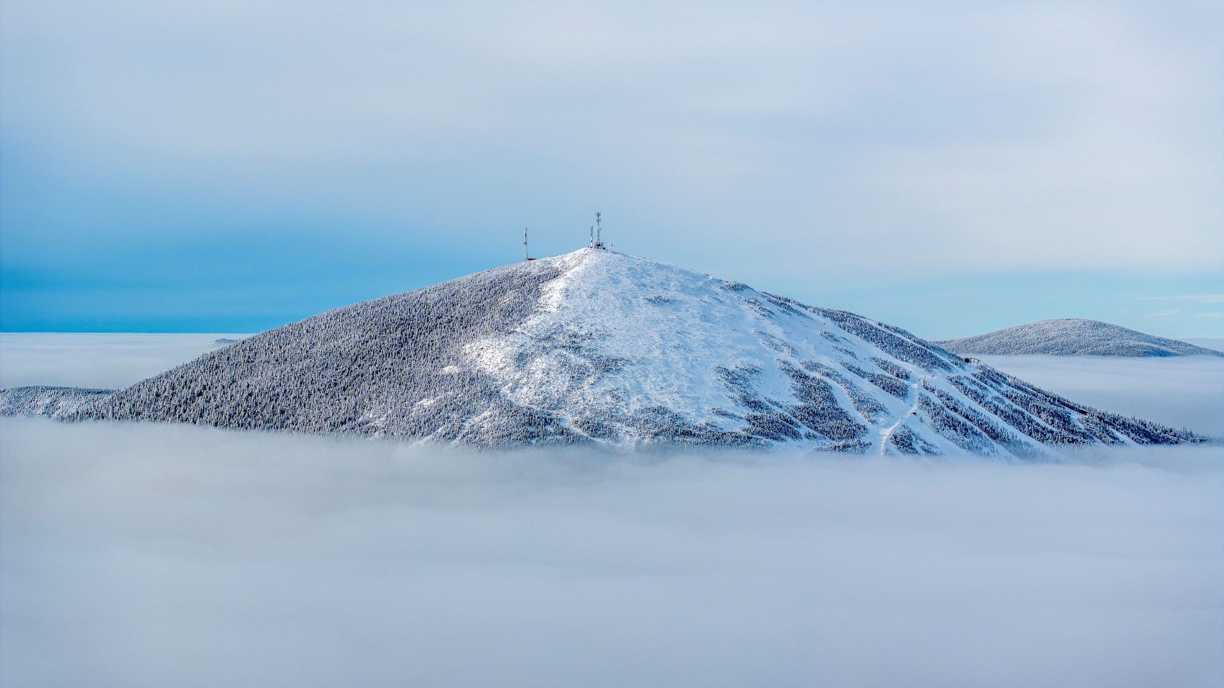 Sugarloaf Mountain in USA - a mountain covered in snow with a cross on top.