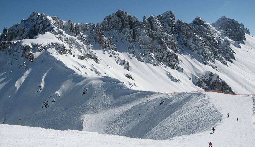 Axamer Lizum in Austria - a group of people skiing down a snow covered mountain.