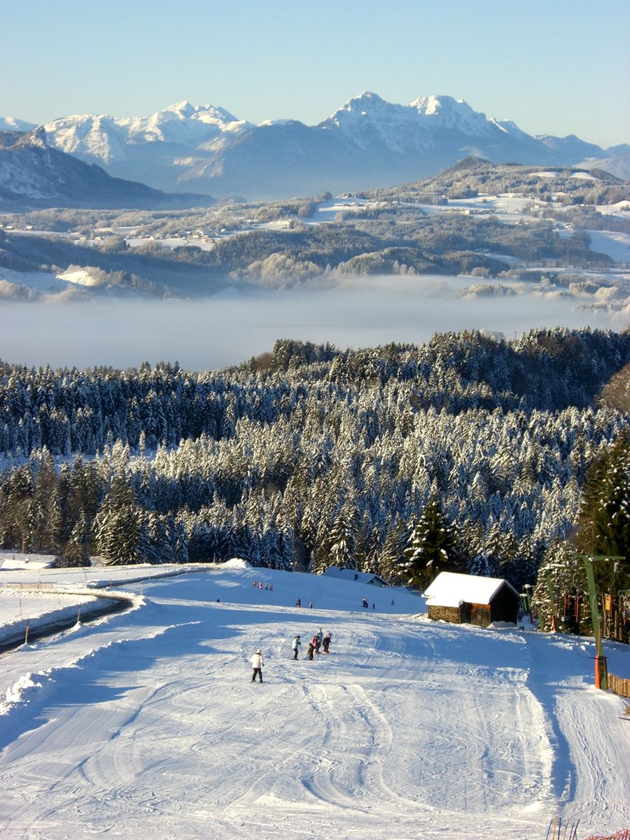 Thalgauberg – Thalgau in Austria - a snow covered ski slope with mountains in the background.