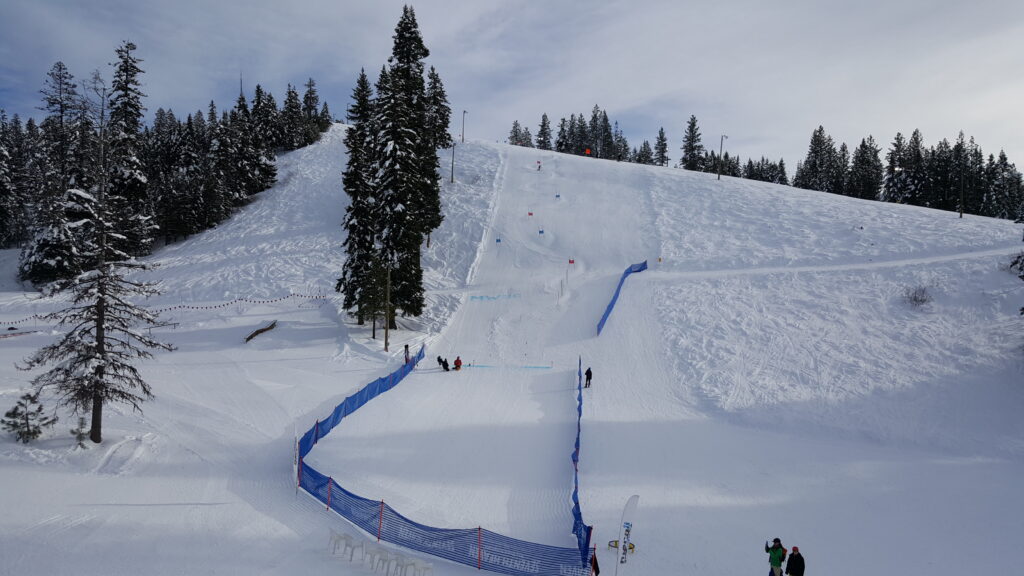 A skier swooshes down a snowy slope at Little Ski Hill Idaho USA. The ski resort's chalet and lift are also visible encompassing a winter sports scene.