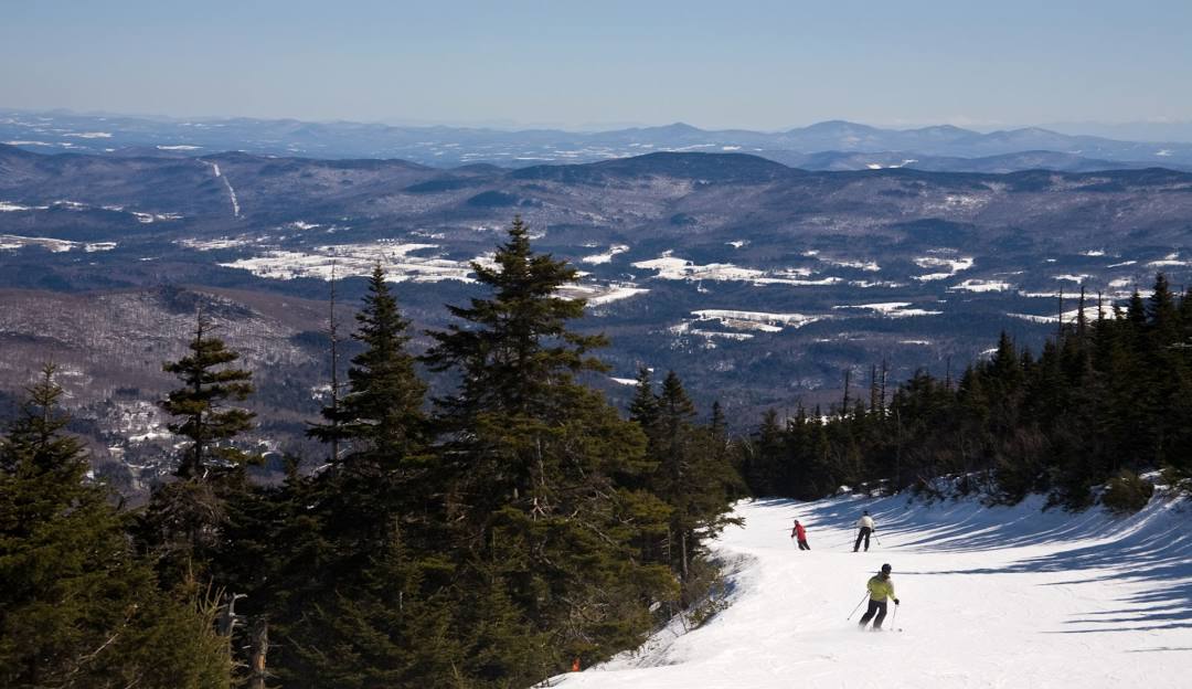 Sugarbush Resort in USA - a person skiing down a snowy slope in the mountains.