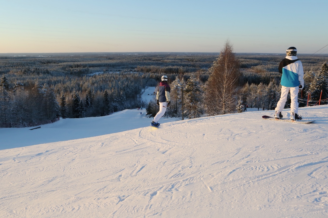 Parra in Finland - a group of people skiing down a snowy hill.
