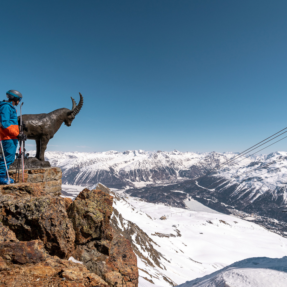 Müsella – La Punt in Switzerland - a man sitting on top of a mountain with a dog.