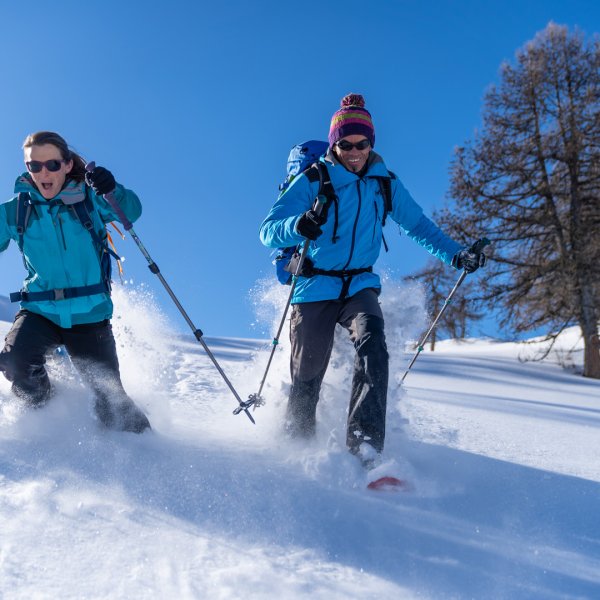 Winter scene at Puy Saint Vincent, France, featuring a family and a group of people skiing amidst pristine snow-covered slopes, with a quaint challet in the background.