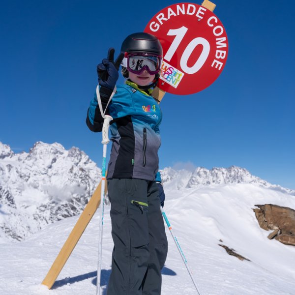 A skier gliding down the snowy slopes in Puy Saint Vincent, France with a cozy chalet in the background.