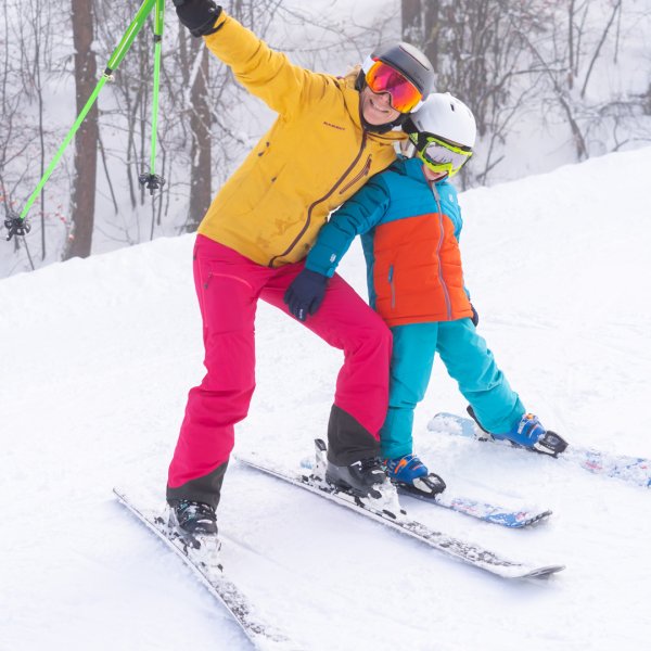 A skier and a family enjoying winter sports in the picturesque Puy Saint Vincent in Briançon France including a child learning to ski and a snowboarder.