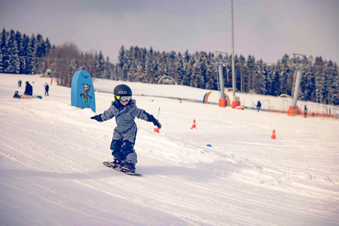 Wexl Arena – St Corona am Wechsel in Austria - a little boy riding a snowboard down a hill.