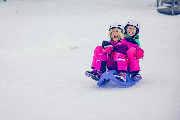 Wexl Arena – St Corona am Wechsel in Austria - a little girl riding a sler down a hill.