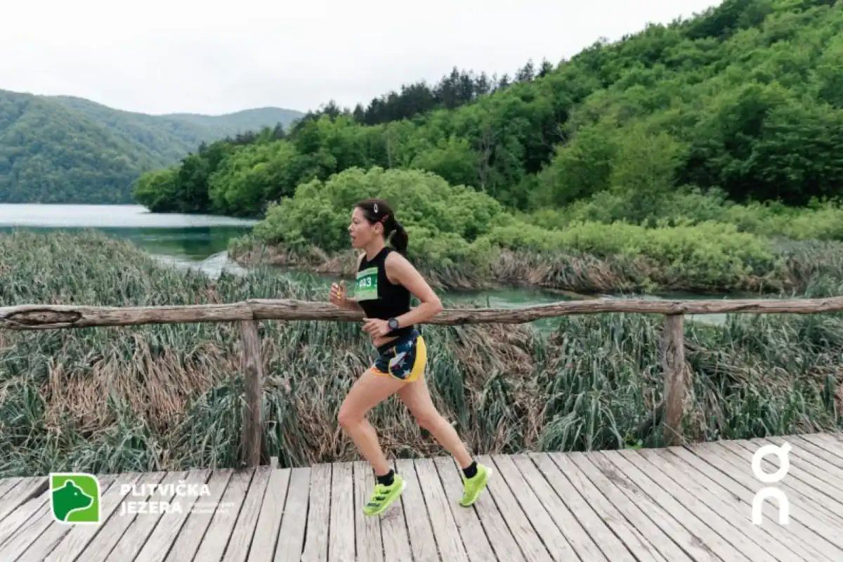 ŠRC Mukinje in Croatia - a woman running on a wooden bridge over a lake.