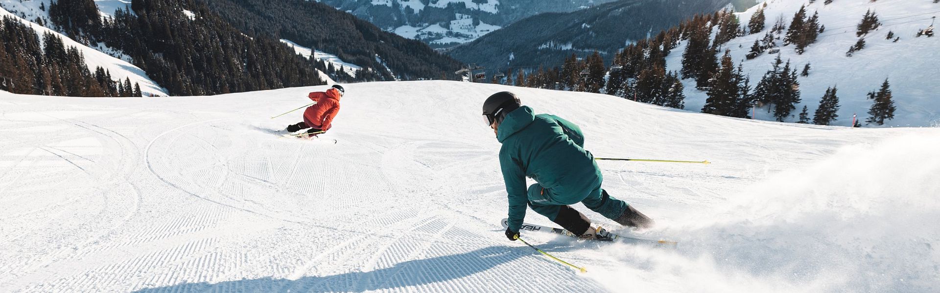 KitzSki in Austria - two people skiing down a snow covered mountain.