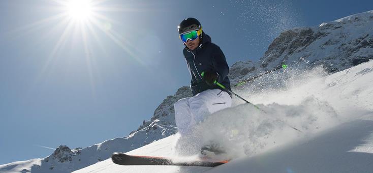 A skier gliding down the snowy slopes of Watles – Malles Venosta in South Tyrol, Italy. Winter sports enthusiasts and a cozy challet embellish the picturesque winter scene.