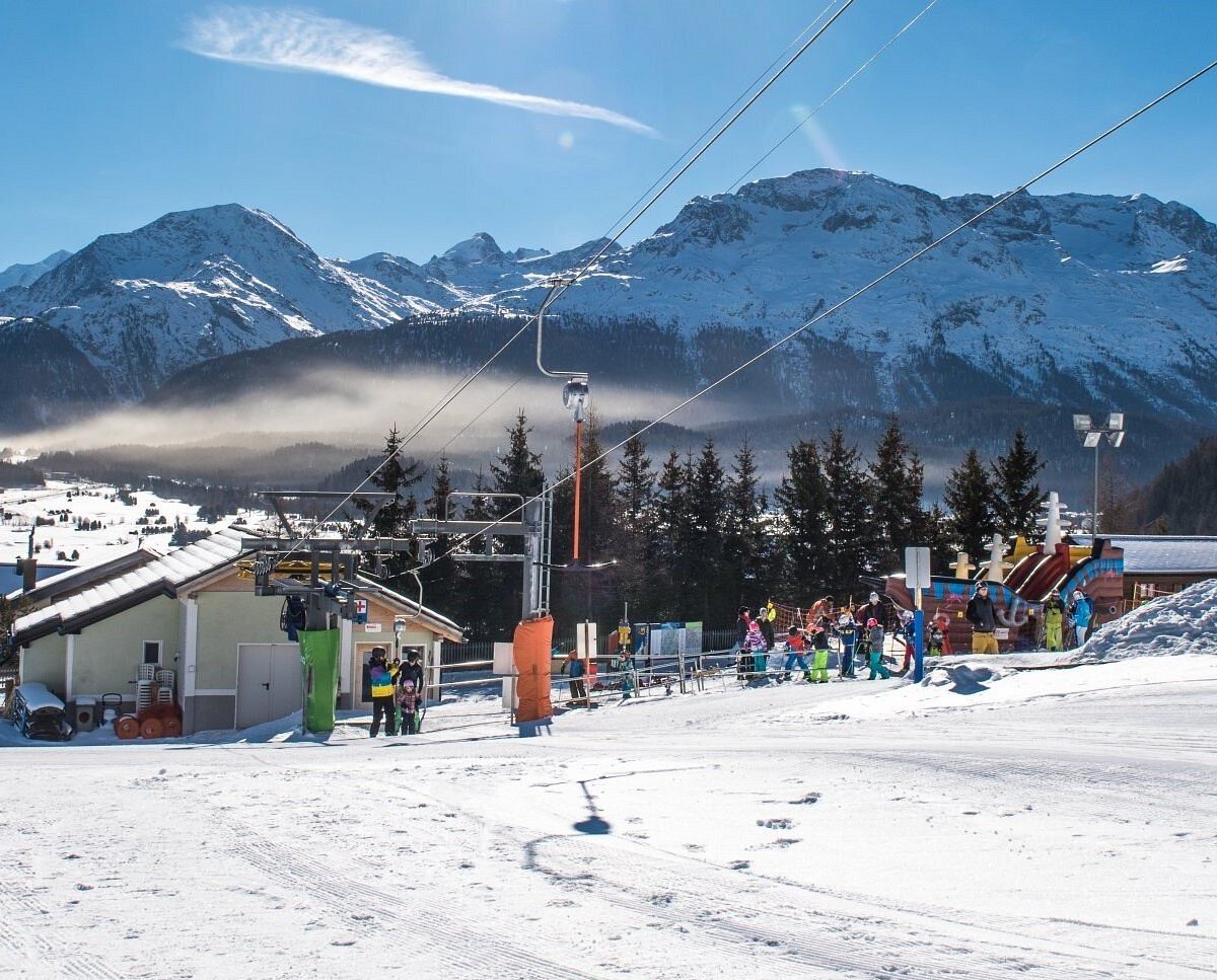 Survih – Samedan in Switzerland - a ski slope with people walking on it.