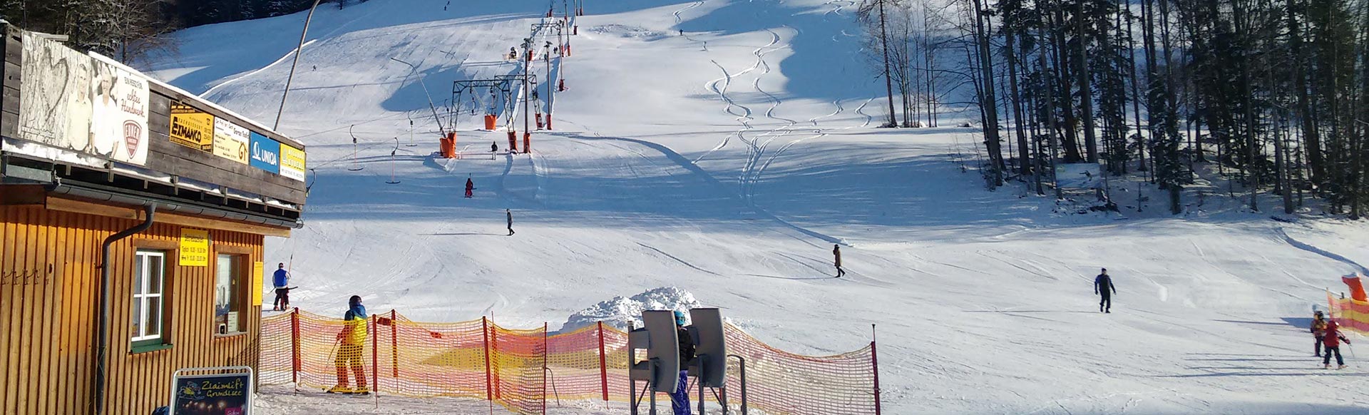 Zlaim – Grundlsee in Austria - a ski slope with people skiing down it.