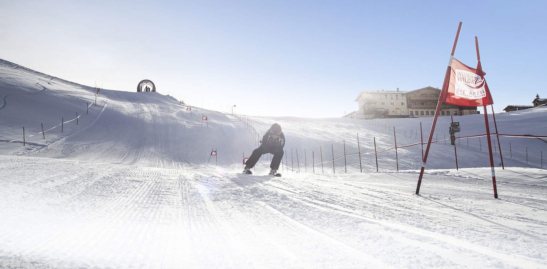 Wildkogel in Austria - a man riding a snowboard down a snow covered slope.