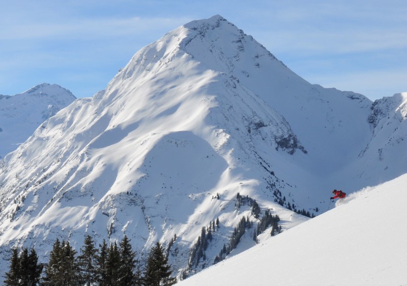 A picturesque winter scene in Gstaad Bern Espace Mittelland Switzerland featuring a prominent mountain covered in snow a skier enjoying the slopes and a charming chalet nestled amidst this breathtaking landscape.
