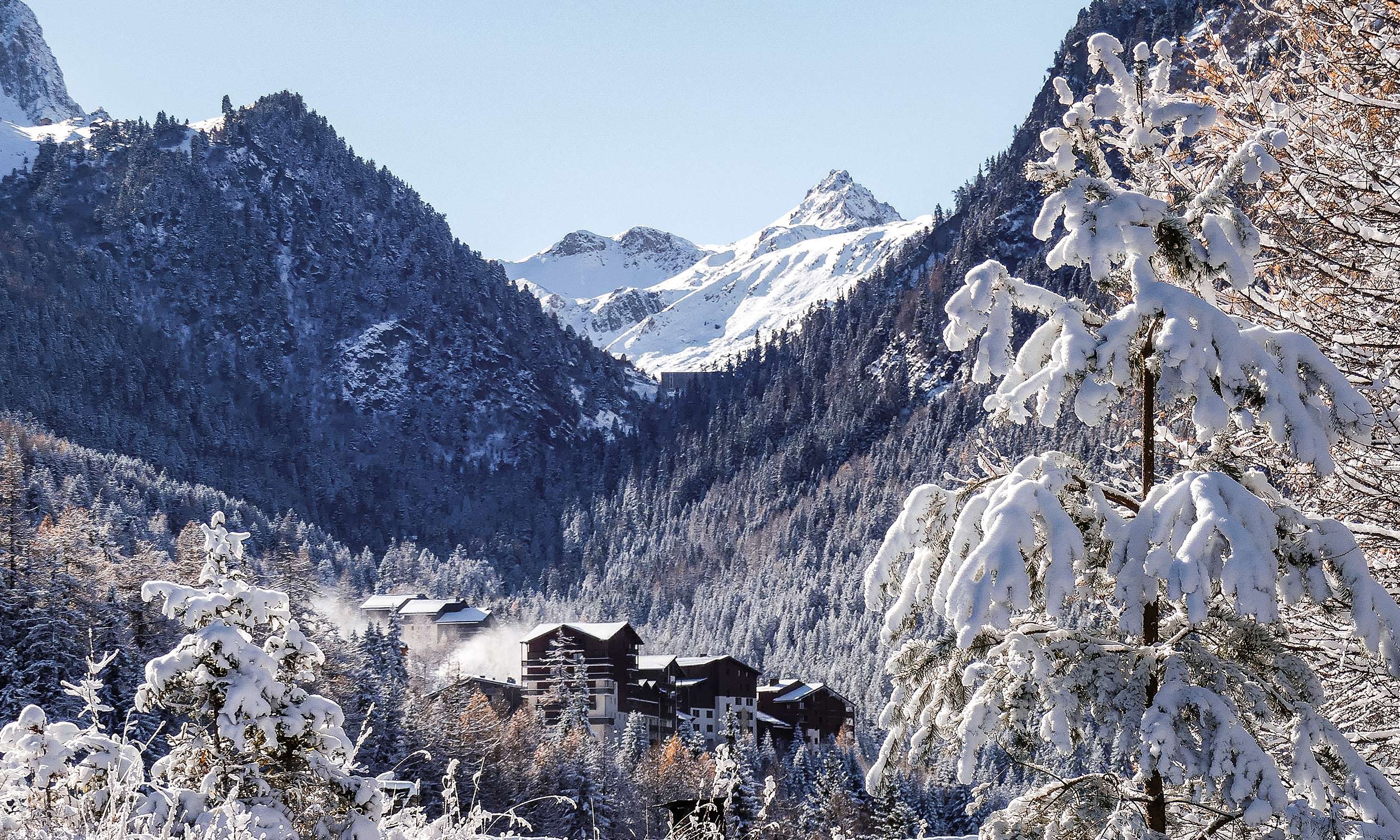 Winter sports enthusiasts enjoying at Valfréjus ski resort in Savoie Mont Blanc, France. Scenic winter landscape with a mountain hut and a charming chalet in the foreground.