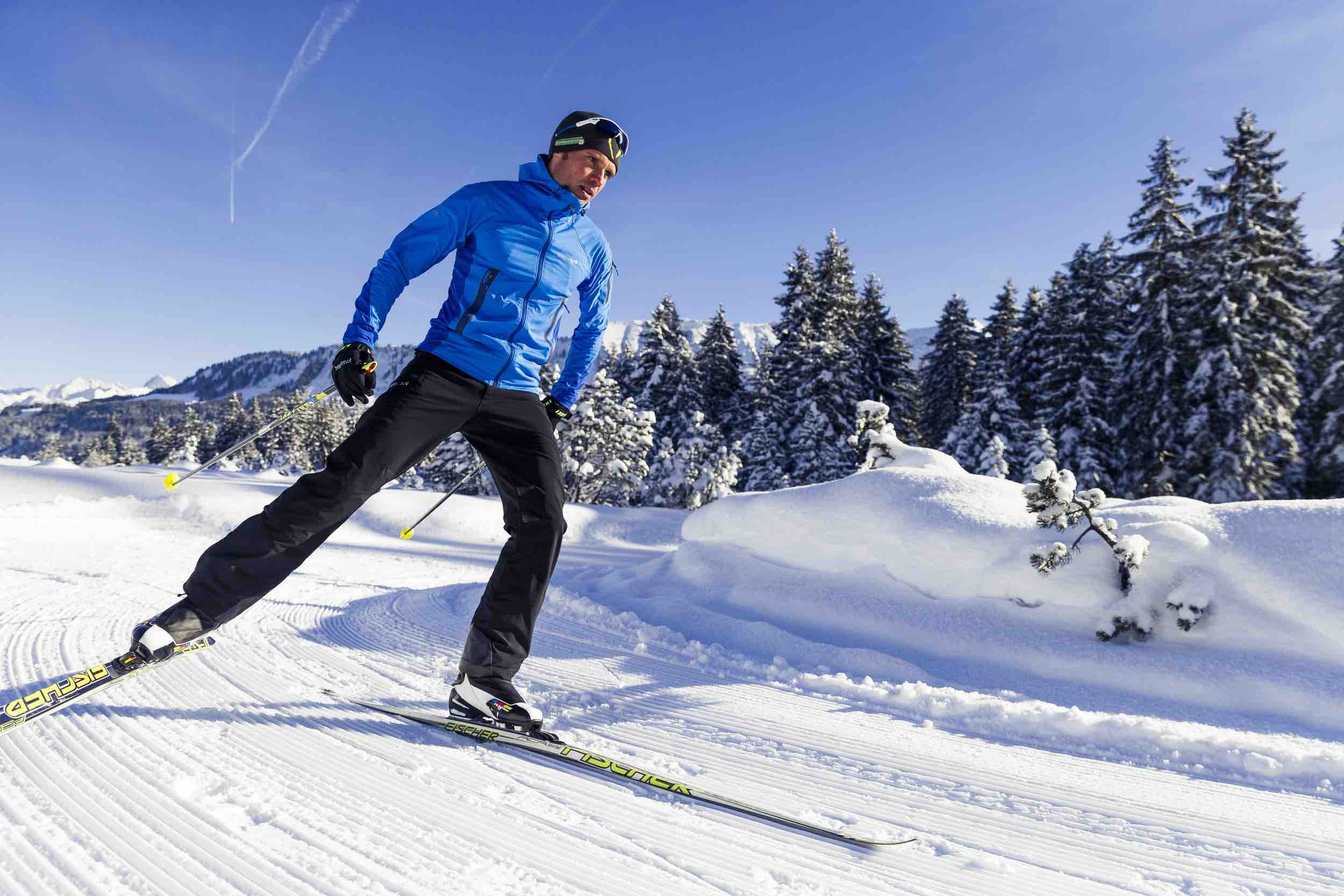 A skier enjoys a winter sports scene in Walmendingerhorn | ​Heuberg – Mittelberg | ​Hirschegg, Bregenz, Vorarlberg, Austria, with a challet peeking through the snowy landscape.