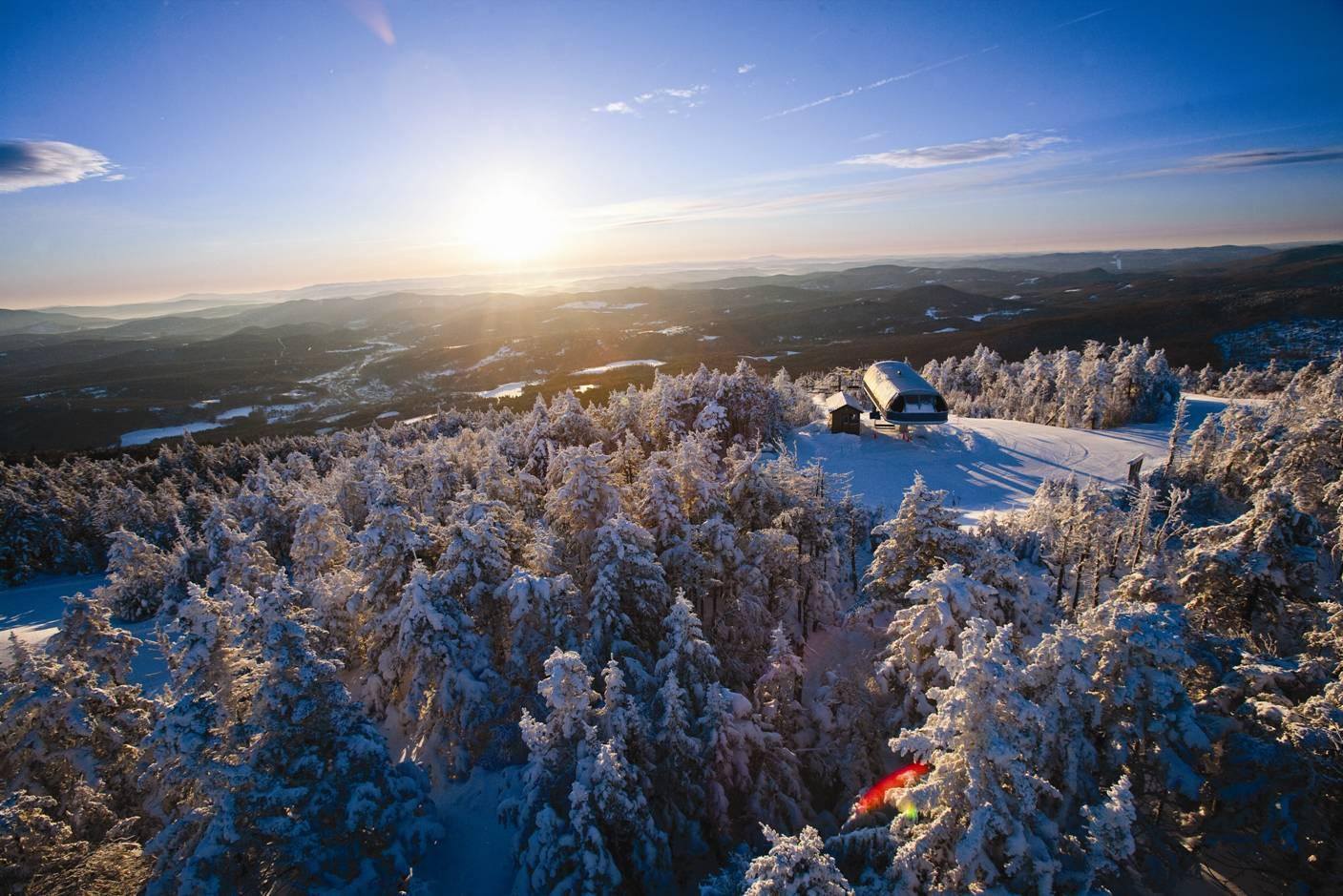 Okemo Mountain Resort in USA - a person skiing down a snowy slope at sunset.