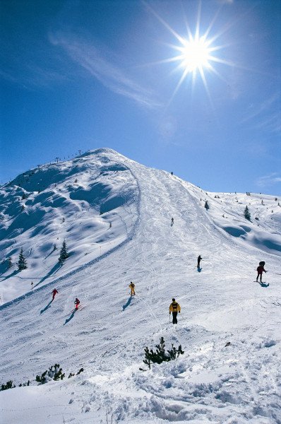 Paganella – Andalo in Italy - a group of people skiing down a snow covered mountain.