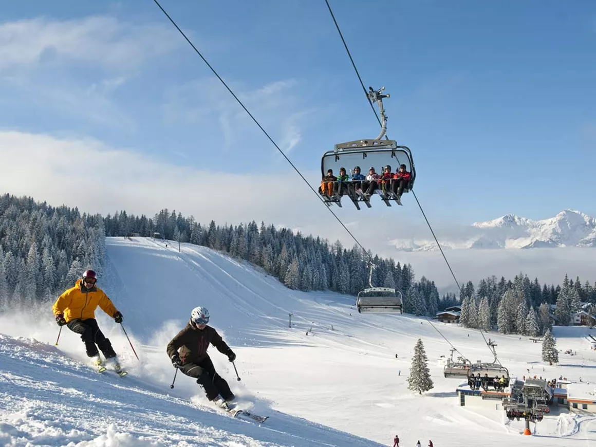 Wurzeralm – Spital am Pyhrn in Austria - two people are skiing down a snowy slope.