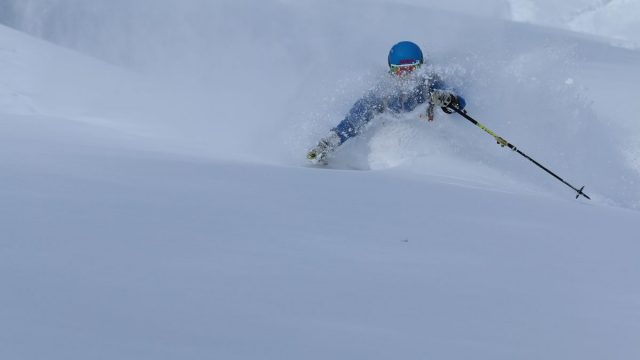 A skier gliding down snowy slopes at Wurzeralm – Spital am Pyhrn, a ski resort in Upper Austria, set against a backdrop of a quaint chalet.