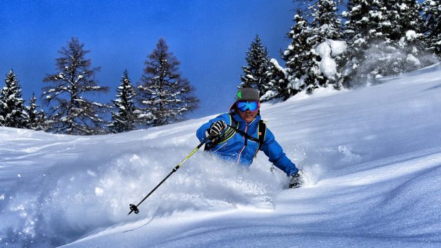 A skier in action at the Wurzeralm – Spital am Pyhrn in Steyr-Kirchdorf Austria. A quintessential winter sports scene further accentuated by the presence of a chalet and ski resort.