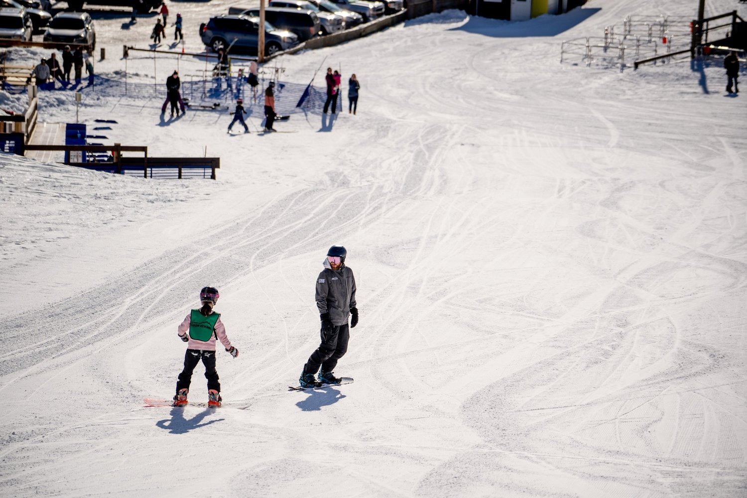 A winter sports scene at Hart Highlands in Northern British Columbia, Canada, featuring a skier and a family enjoying skiing at the ski resort.