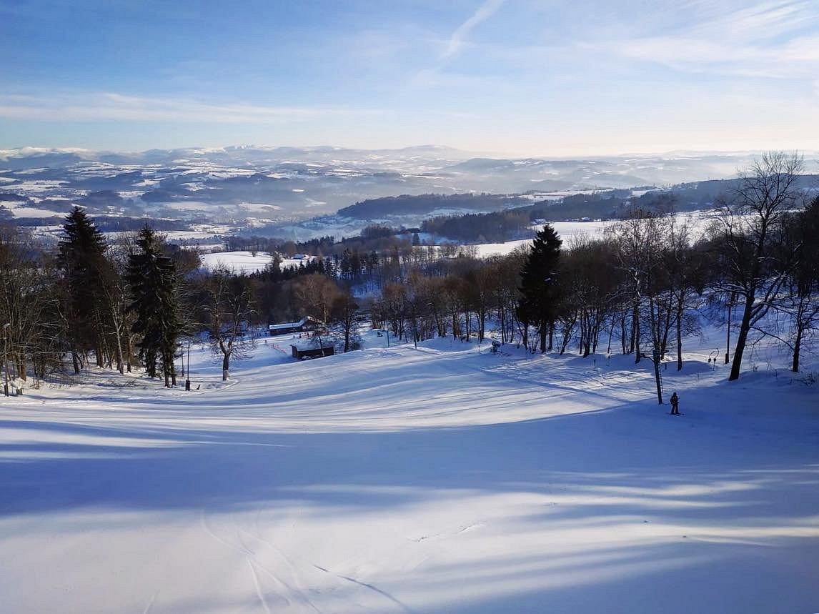 Kozákov in Czech Republic - a snowy landscape with trees and mountains in the background.
