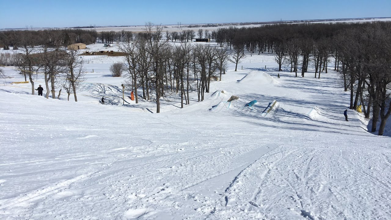 A skier indulges in winter sports at Stony Mountain in Manitoba, Canada. The bustling ski resort is blanketed with fresh snow, juxtaposing the lively snowmobile driven area.