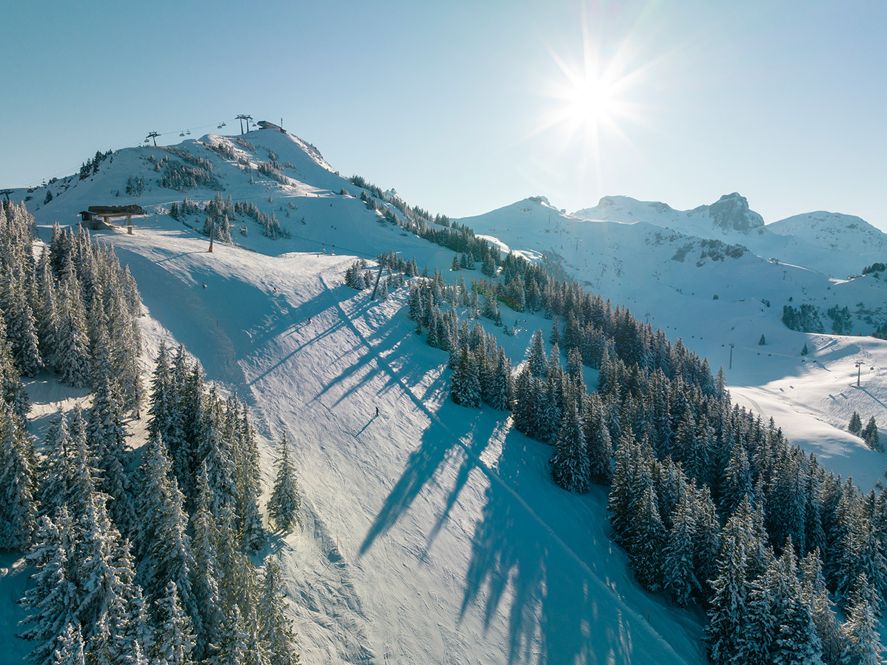 A winter sports scene at Flumserberg ski resort in Eastern Switzerland, featuring a skier enjoying the snow-covered slopes and a nearby ski lift.