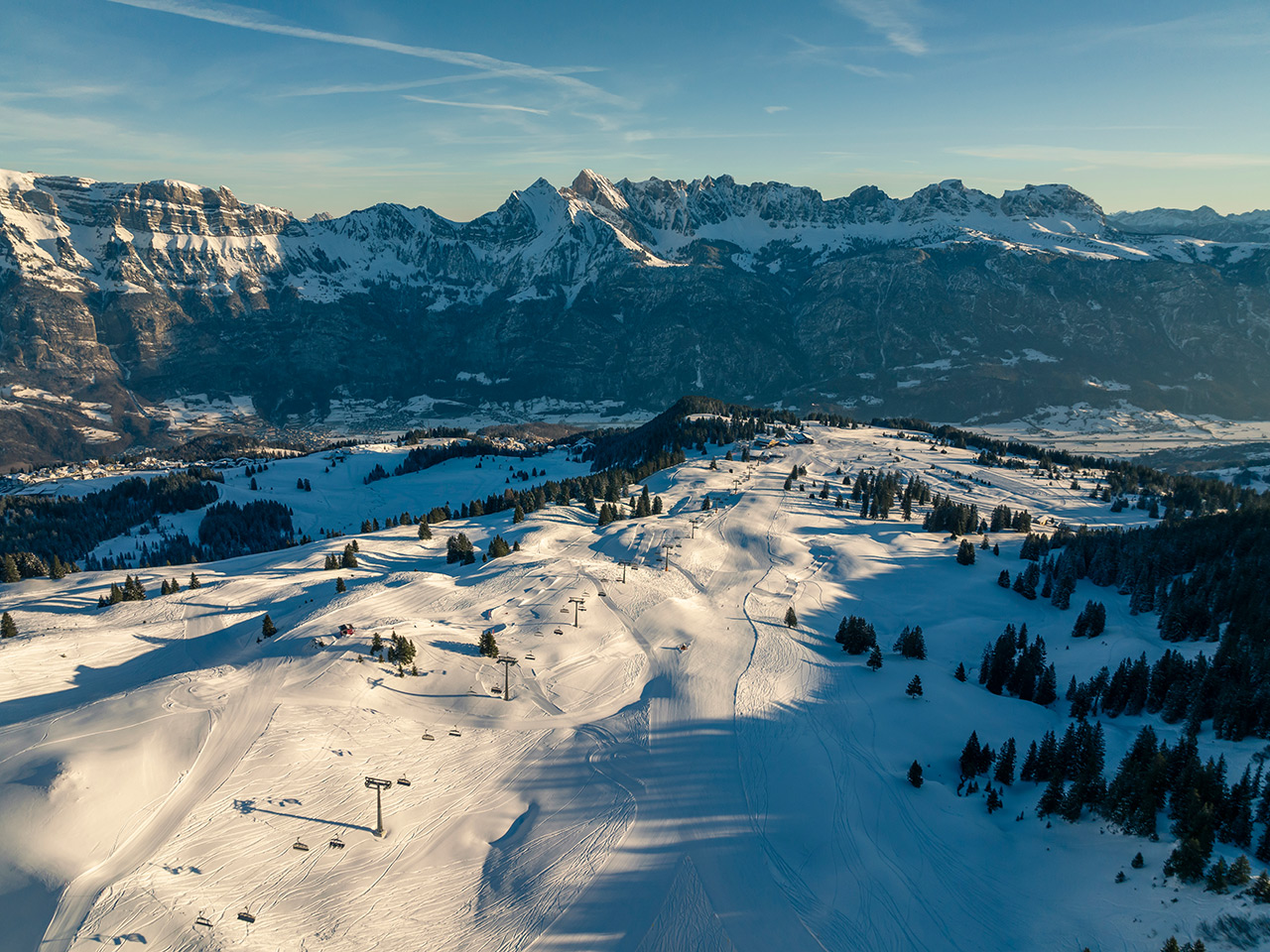 Ski resort in Flumserberg, Eastern Switzerland features a bustling winter sports scene. Snow-covered slopes under a blue sky beckon skiers while a charming chalet adds to the winter ambiance.