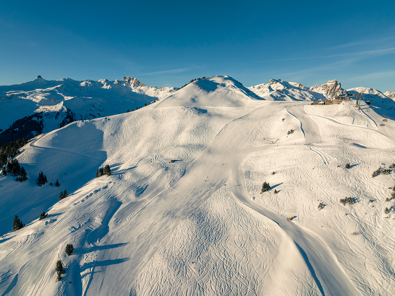 Winter scene at Flumserberg ski resort in Eastern Switzerland showcasing a bustling sports scene on snow-covered slopes of a prominent mountain.