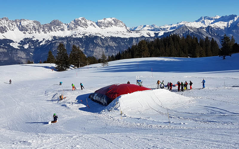 Winter sports scene at Flumserberg in Heidiland, Switzerland showcasing a bustling ski resort with a charming chalet in the background.