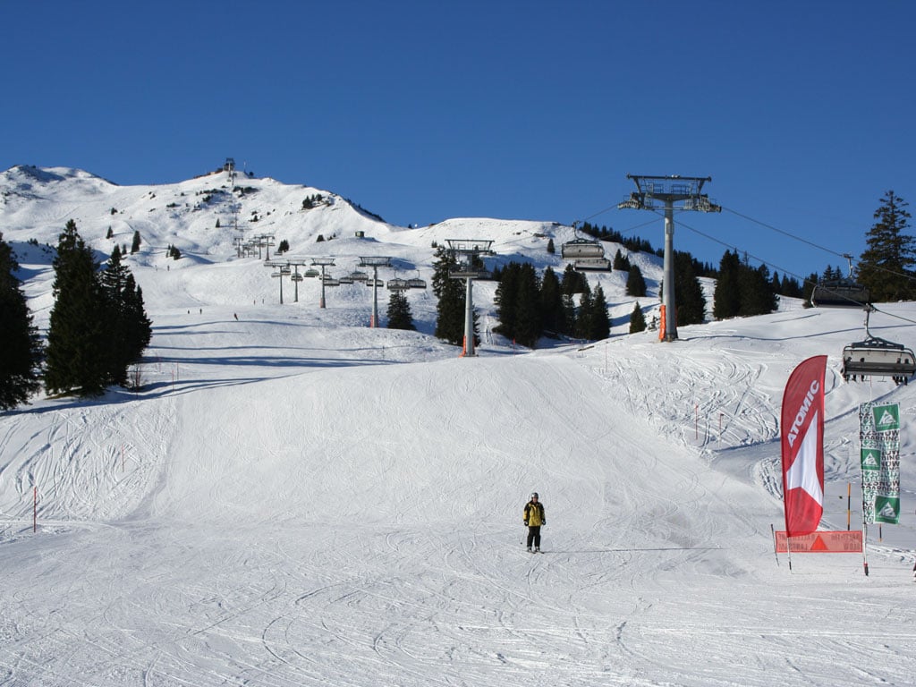 Winter scene at Flumserberg ski resort in Eastern Switzerland, featuring a chalet and a skier in action amidst a breathtaking snowy landscape.