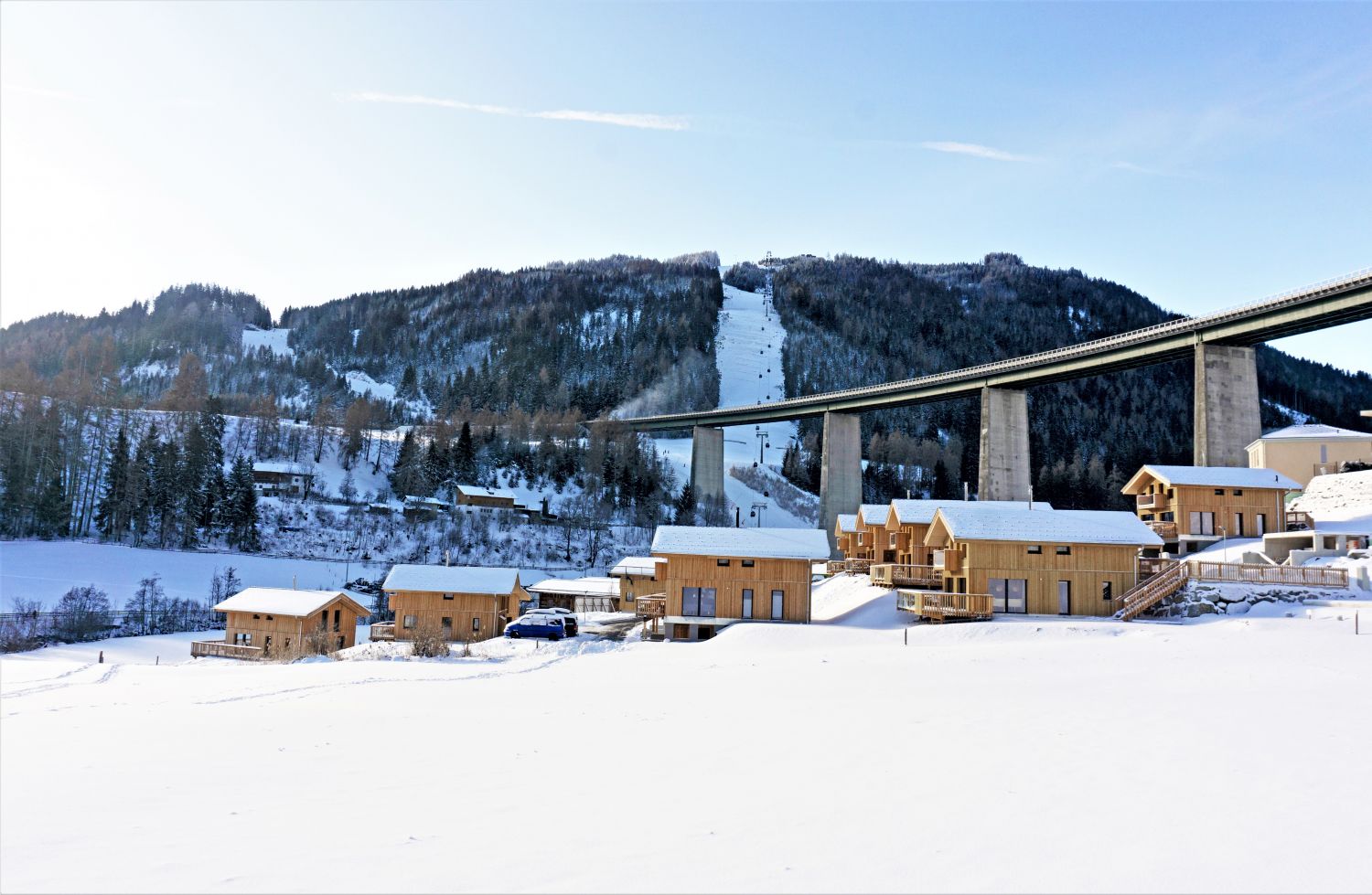 Arena Bergeralm in Austria - a snow covered village with a bridge in the background.