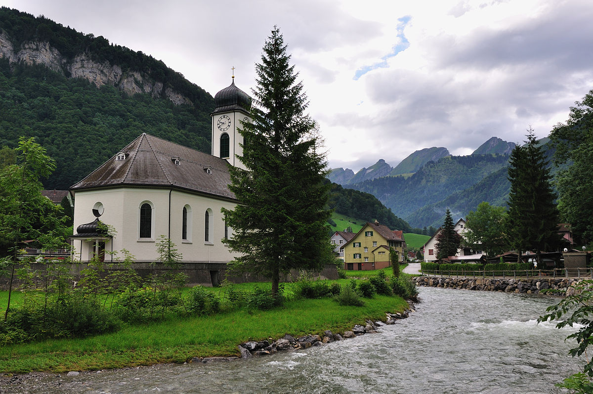 Oberhelfenschwil in Switzerland - a small church sits on the side of a river.
