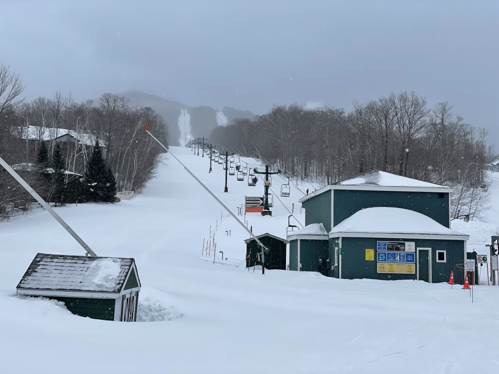 Smugglers' Notch Resort in USA: a ski slope covered in snow next to a building.