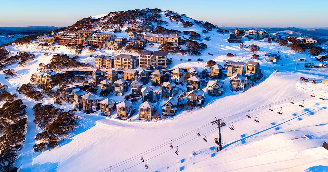 A scenic view of Dinner Plain ski resort in Victoria, Australia, featuring snow-covered slopes and a stunning winter landscape, characteristic of a bustling winter sports scene.