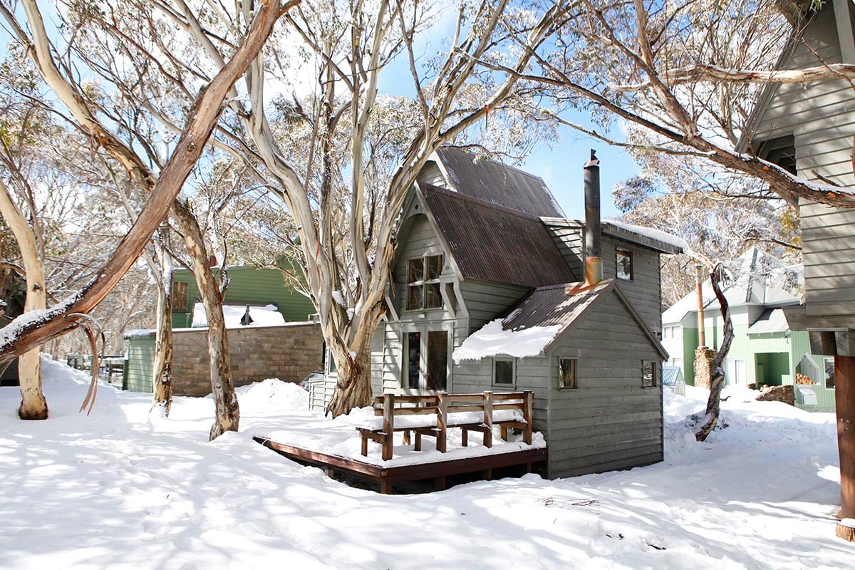 Image showing a cozy lodge nestled in Dinner Plain, Victoria in Australia, surrounded by a stunning winter panorama. Snow-dusted trees and winter sports scene fill the landscape.