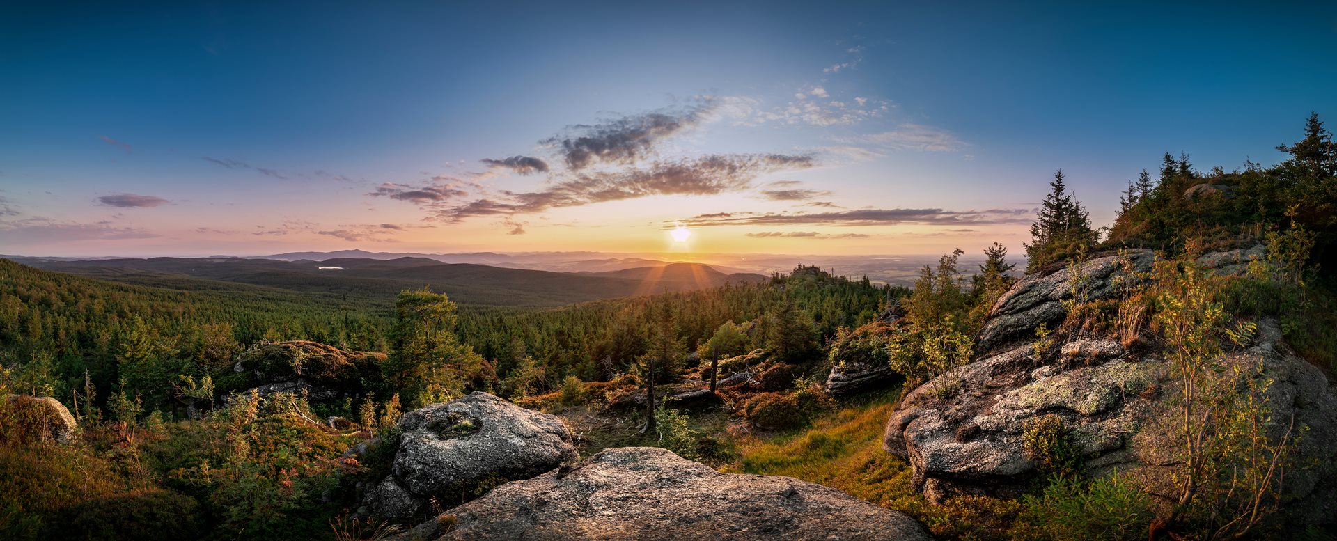 Křemešník in Czech Republic - the sun is setting over the mountains and trees.
